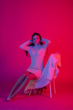 Chihuahua köpeğiyle poz veren bir kız. Neon ışıklı, kırmızı ve mavi elbiseli güzel esmer kadın. Renkli parlak neon renkli, mavi ve mor ışıklı bir kadın. Doğal dudakları olan muhteşem bir esmer. renk filtreleri.