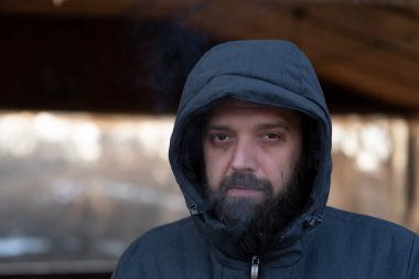 Sokakta gri ceketli sakallı bir adam. Bir adamın portresi. Sakallı adam. Kış, kışlık ceket, sakal. Kapüşonlu bir adamın portresi