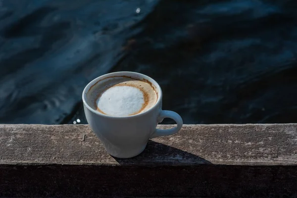 Coffee selective focus. White cup with cappuccino on the nature. White cup with cappuccino, coffee, morning, cheerfulness.