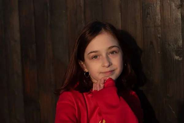 一个漂亮的9岁小女孩的近照 一个快乐 自信的9岁女孩的画像 穿着红色运动衫 木制背景的青少年 红头发的女孩 — 图库照片