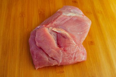 Tahta kesme tahtasında pişmemiş hindi filetosu. Tahta kesme tahtasının üzerinde çiğ hindi göğsü, yakın çekim manzarası. Tahtada hindi filetosu. Eko et, sağlıklı et, yemek fotoğrafçılığı. Yemek pişirme