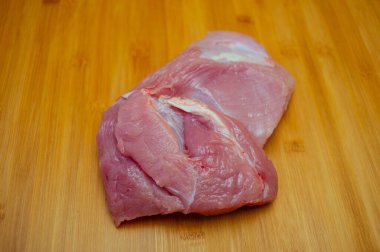 Tahta kesme tahtasında pişmemiş hindi filetosu. Tahta kesme tahtasının üzerinde çiğ hindi göğsü, yakın çekim manzarası. Tahtada hindi filetosu. Eko et, sağlıklı et, yemek fotoğrafçılığı. Yemek pişirme