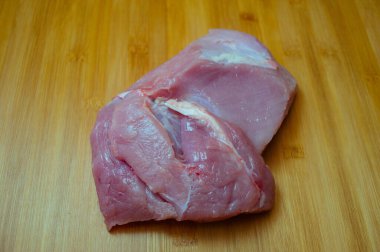 Tahta kesme tahtasında pişmemiş hindi filetosu. Tahta kesme tahtasının üzerinde çiğ hindi göğsü, yakın çekim manzarası. Tahtada hindi filetosu. Eko et, sağlıklı et, yemek fotoğrafçılığı. Yemek pişirme