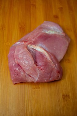 Tahta kesme tahtasında pişmemiş hindi filetosu. Tahta kesme tahtasının üzerinde çiğ hindi göğsü, yakın çekim manzarası. Tahtada hindi filetosu. Eko et, sağlıklı et, yemek fotoğrafçılığı. Yemek pişirme