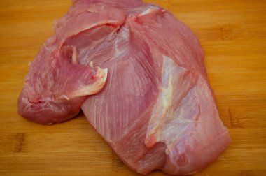 Tahta kesme tahtasında pişmemiş hindi filetosu. Tahta kesme tahtasının üzerinde çiğ hindi göğsü, yakın çekim manzarası. Tahtada hindi filetosu. Eko et, sağlıklı et, yemek fotoğrafçılığı. Yemek pişirme