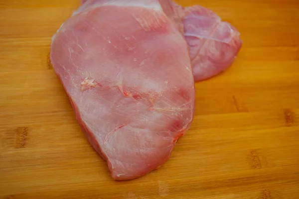 新鲜的未煮熟的火鸡片放在木板上 烤火鸡胸肉放在木制切菜板上 近距离观察 土耳其片在木板上 生态肉类 健康肉类 食品摄影 — 图库照片