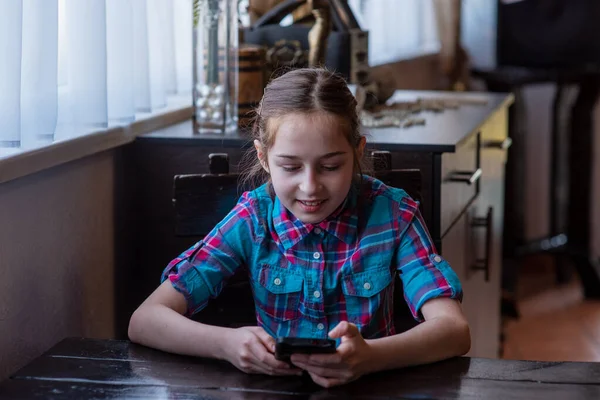 The Internet. Message. Girl in a cafe with a smartphone. The child looks in the smartphone. Gadgets and kids. A teenager runs his video blog. A blogger is looking at his gadget. Girl 9 years old.