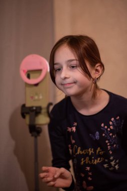 Mutlu genç bir kadın beyaz arka planda selfie çekiyor. Kız monopod ya da selfie çubuğuyla kendi videosunu çekiyor. Blogcu. Vlog. Kız internet ya da internet ağları için video çekiyor. Portre