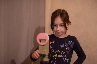 Mutlu genç bir kadın beyaz arka planda selfie çekiyor. Kız monopod ya da selfie çubuğuyla kendi videosunu çekiyor. Blogcu. Vlog. Kız internet ya da internet ağları için video çekiyor. Portre