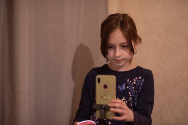 Mutlu genç bir kadın beyaz arka planda selfie çekiyor. Kız monopod ya da selfie çubuğuyla kendi videosunu çekiyor. Blogcu. Vlog. Kız internet ya da internet ağları için video çekiyor. Portre