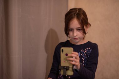Mutlu genç bir kadın beyaz arka planda selfie çekiyor. Kız monopod ya da selfie çubuğuyla kendi videosunu çekiyor. Blogcu. Vlog. Kız internet ya da internet ağları için video çekiyor. Portre