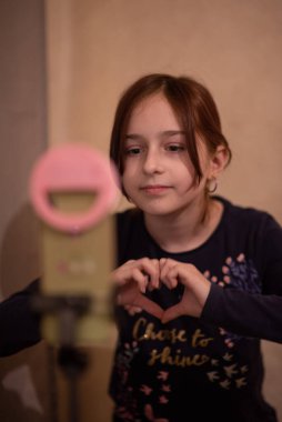 Mutlu genç bir kadın beyaz arka planda selfie çekiyor. Kız monopod ya da selfie çubuğuyla kendi videosunu çekiyor. Blogcu. Vlog. Kız internet ya da internet ağları için video çekiyor. Portre