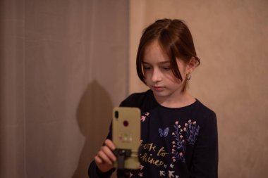 Mutlu genç bir kadın beyaz arka planda selfie çekiyor. Kız monopod ya da selfie çubuğuyla kendi videosunu çekiyor. Blogcu. Vlog. Kız internet ya da internet ağları için video çekiyor. Portre