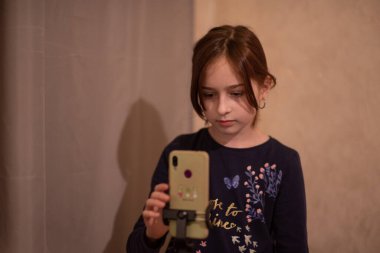 Mutlu genç bir kadın beyaz arka planda selfie çekiyor. Kız monopod ya da selfie çubuğuyla kendi videosunu çekiyor. Blogcu. Vlog. Kız internet ya da internet ağları için video çekiyor. Portre