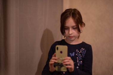 Mutlu genç bir kadın beyaz arka planda selfie çekiyor. Kız monopod ya da selfie çubuğuyla kendi videosunu çekiyor. Blogcu. Vlog. Kız internet ya da internet ağları için video çekiyor. Portre