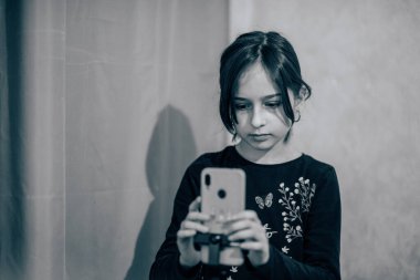 Mutlu genç bir kadın beyaz arka planda selfie çekiyor. Kız monopod ya da selfie çubuğuyla kendi videosunu çekiyor. Blogcu. Vlog. Kız internet ya da internet ağları için video çekiyor. Portre