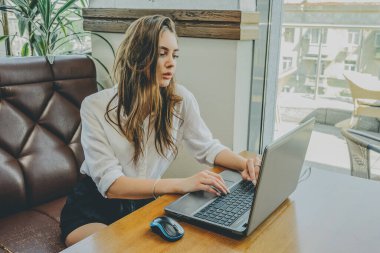 Genç bayan kafede internette geziniyor. Kafede dizüstü bilgisayarlı bir kız. Ofisinde aleti olan esmer bir kız. Bir kadın bilgisayara bakıyor. Beyaz gömlekli kız. 18-19 yaşlarında bir kız.