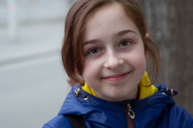 Mavi ceketli güzel, genç bir kadın şehir arka planında poz veriyor. Mavi bir ceket. 9 yaşında. 9 yaşında, mavi ceketli bir kız.