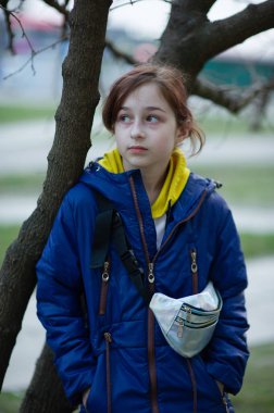 Mavi ceketli güzel, genç bir kadın şehir arka planında poz veriyor. Mavi bir ceket. 9 yaşında. 9 yaşında, mavi ceketli bir kız.