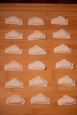 Köfteli ahşap bir arka plan. Kahverengi mutfak tahtasındaki yemek ve mutfak aletleri. Hamur pişirme kavramı. Tahtadaki hamur köfteleri. Peynirli çiğ hamur tatlısı. Hazırlama hamur tatlısı
