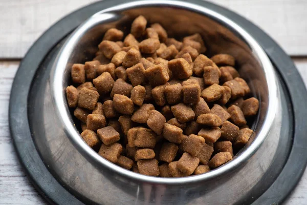 Animal food. Cat or dog food in a plate. Cat or dog food in a metal plate a plate on a wooden floor or window sill. Pet food for pets. Dry food for the health of dogs and cats.