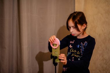 Mutlu genç bir kadın beyaz arka planda selfie çekiyor. Kız monopod ya da selfie çubuğuyla kendi videosunu çekiyor. Blogcu. Vlog. Kız internet ya da internet ağları için video çekiyor. Portre