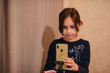 Mutlu genç bir kadın beyaz arka planda selfie çekiyor. Kız monopod ya da selfie çubuğuyla kendi videosunu çekiyor. Blogcu. Vlog. Kız internet ya da internet ağları için video çekiyor. Portre