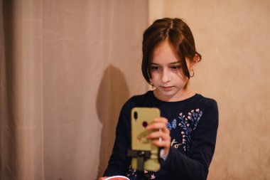 Mutlu genç bir kadın beyaz arka planda selfie çekiyor. Kız monopod ya da selfie çubuğuyla kendi videosunu çekiyor. Blogcu. Vlog. Kız internet ya da internet ağları için video çekiyor. Portre