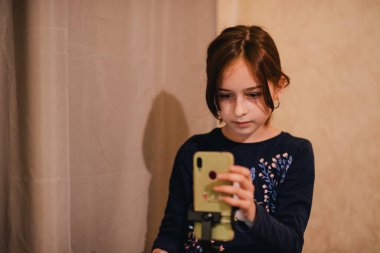 Mutlu genç bir kadın beyaz arka planda selfie çekiyor. Kız monopod ya da selfie çubuğuyla kendi videosunu çekiyor. Blogcu. Vlog. Kız internet ya da internet ağları için video çekiyor. Portre