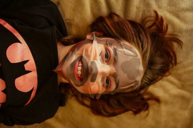 Kız yüz maskesi yapmış. Kız 9 yaşında ya da 10 yaşında. Neşe içinde yüz bakımı. Kız yüzü için yararlı maddelerle selüloz bir maske yaptı. Ergen