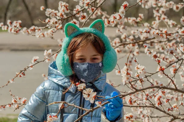 Woman in protective mask outdoors. Masked girl outdoors. Virus, mask, spring. Girl 9 years old. Street. Protection against viruses and bacteria. Medical respiratory mask. Epidemic. Protection