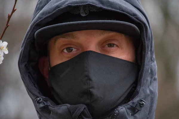 A man wearing a black respiratory mask on his face. A man in the street in a black mask. Virus. Coronavirus. A guy in the spring on the street in a respiratory mask to protect against infection virus