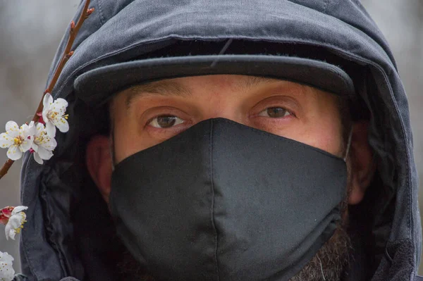 A man wearing a black respiratory mask on his face. A man in the street in a black mask. Virus. Coronavirus. A guy in the spring on the street in a respiratory mask to protect against infection virus