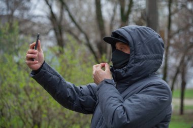 Yüzüne siyah solunum maskesi takan bir adam. Coronavirus. Enfeksiyon virüsünden korunmak için sokakta solunum maskesi takan bir adam. Bir adam kendini akıllı telefondan fotoğraflıyor..