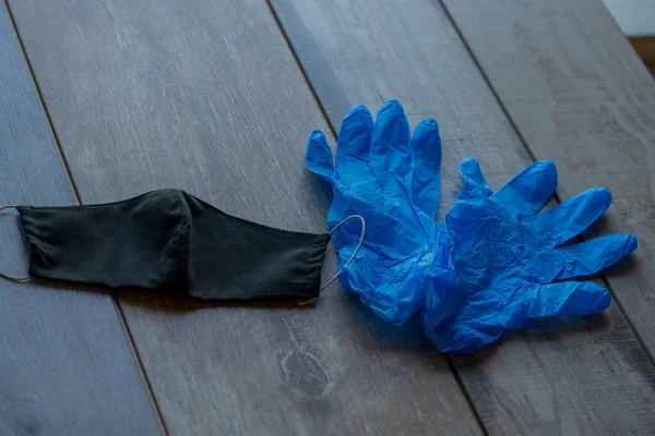 A protective half mask is lying on the table next to a pair of disposable gloves. Protective items to help fight the virus. Mask and gloves crown virus