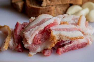 Sarımsaklı pastırma. Çavdar ekmekli sarımsak. Beyaz tahtada dilimlenmiş pastırma, sarımsak ve ekmek..