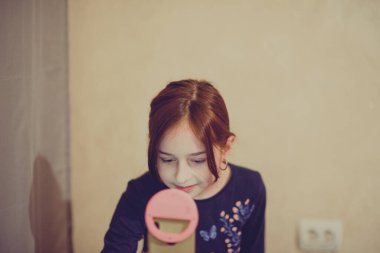 Mutlu genç bir kadın beyaz arka planda selfie çekiyor. Kız monopod ya da selfie çubuğuyla kendi videosunu çekiyor. Blogcu. Vlog. Kız internet ya da internet ağları için video çekiyor. Portre