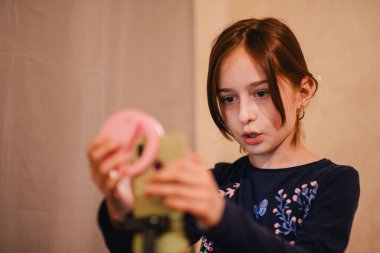 Mutlu genç bir kadın beyaz arka planda selfie çekiyor. Kız monopod ya da selfie çubuğuyla kendi videosunu çekiyor. Blogcu. Vlog. Kız internet ya da internet ağları için video çekiyor. Portre