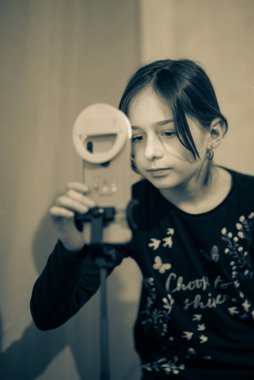 Mutlu genç bir kadın beyaz arka planda selfie çekiyor. Kız monopod ya da selfie çubuğuyla kendi videosunu çekiyor. Blogcu. Vlog. Kız internet ya da internet ağları için video çekiyor. Portre