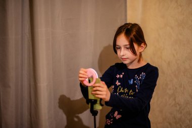 Mutlu genç bir kadın beyaz arka planda selfie çekiyor. Kız monopod ya da selfie çubuğuyla kendi videosunu çekiyor. Blogcu. Vlog. Kız internet ya da internet ağları için video çekiyor. Portre