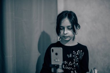 Mutlu genç bir kadın beyaz arka planda selfie çekiyor. Kız monopod ya da selfie çubuğuyla kendi videosunu çekiyor. Blogcu. Vlog. Kız internet ya da internet ağları için video çekiyor. Portre