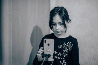 Mutlu genç bir kadın beyaz arka planda selfie çekiyor. Kız monopod ya da selfie çubuğuyla kendi videosunu çekiyor. Blogcu. Vlog. Kız internet ya da internet ağları için video çekiyor. Portre