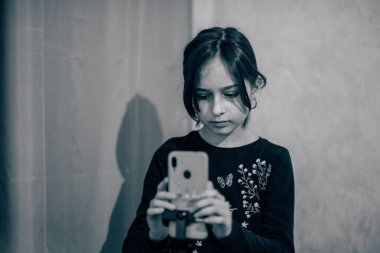 Mutlu genç bir kadın beyaz arka planda selfie çekiyor. Kız monopod ya da selfie çubuğuyla kendi videosunu çekiyor. Blogcu. Vlog. Kız internet ya da internet ağları için video çekiyor. Portre