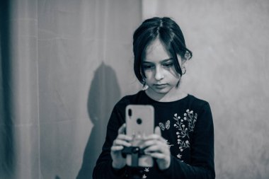 Mutlu genç bir kadın beyaz arka planda selfie çekiyor. Kız monopod ya da selfie çubuğuyla kendi videosunu çekiyor. Blogcu. Vlog. Kız internet ya da internet ağları için video çekiyor. Portre