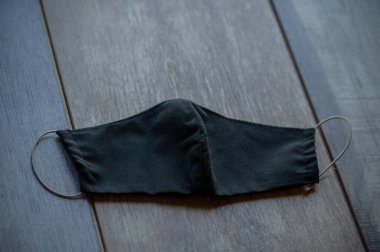 Güvenli nefes alan siyah tekstil maskesi. Hastane ya da kirlilik yüz maskelerini korur. Uzayı kopyala, bakteriden prosedür maskesi. Korunan insanlar. Maske kumaş solunum cihazı masada siyah. Coronavirüs