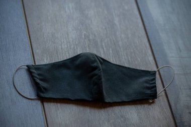 Güvenli nefes alan siyah tekstil maskesi. Hastane ya da kirlilik yüz maskelerini korur. Uzayı kopyala, bakteriden prosedür maskesi. Korunan insanlar. Maske kumaş solunum cihazı masada siyah. Coronavirüs