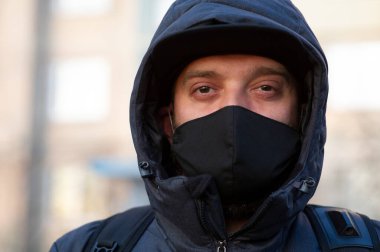 Yüzüne siyah solunum maskesi takan bir adam. Siyah maskeli bir adam sokakta. Virüs. Coronavirus. Enfeksiyon virüsünden korunmak için sokakta solunum maskesi takan bir adam.