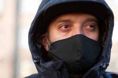 Yüzüne siyah solunum maskesi takan bir adam. Siyah maskeli bir adam sokakta. Virüs. Coronavirus. Enfeksiyon virüsünden korunmak için sokakta solunum maskesi takan bir adam.