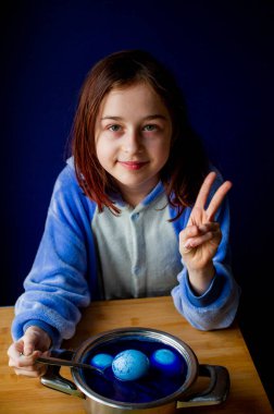 Boyanmış Paskalya Yumurtasını gösteren bir kız. Kız Paskalya için yumurta boyuyor. Mavi yumurta..