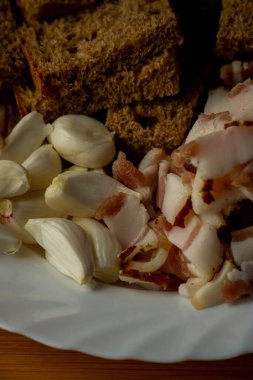 Sarımsak ve pastırma ve sarımsak. Tahtadaki masada pastırma ve sarımsak. Yemek fotoğrafçılığı. Yemek, pastırma, sarımsak ve siyah çavdar ekmeği..